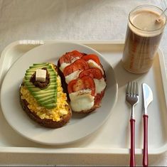 an open faced sandwich with avocado and tomatoes on it next to a drink