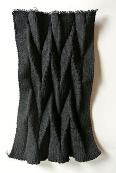 a piece of black knitted material on a white surface