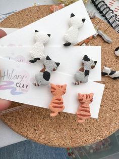 the cat and dog earrings are made out of polymer clay, which has been placed on top of a piece of paper