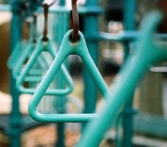 several blue playground swings with brown handles and bars