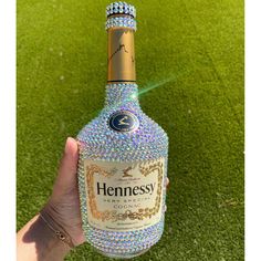 a hand holding a bottle of henness gin on top of a grass covered field