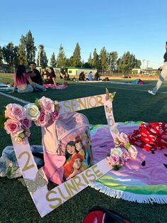 flowers and decorations are laid out on the grass near a sign that reads senior sunrise