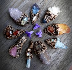 seven different colored stones arranged in a circle on top of a wooden table with purple flowers