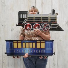 a woman holding a cardboard model of a steam engine train with the word polar express on it