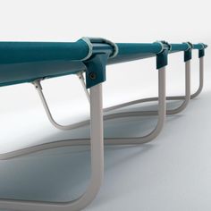 three blue metal benches sitting next to each other on top of a white flooring