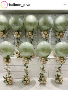 there are many balloons that have been decorated with greenery and gold balls on them