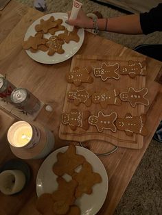 a wooden table topped with lots of cut up gingerbreads next to a candle