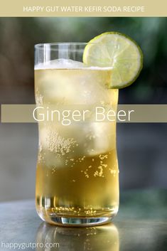 a tall glass filled with ginger beer next to a lime slice