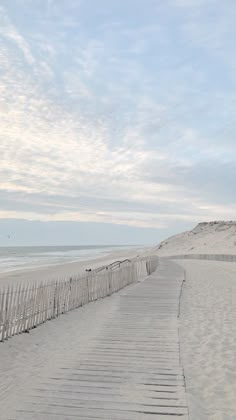 a wooden walkway leading to the beach with white sand and blue sky in the background