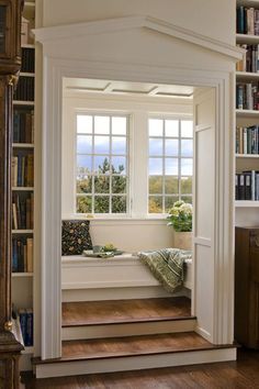 a window seat in the corner of a room with bookshelves and shelves full of books