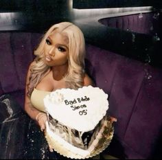 a woman sitting on top of a purple couch holding a cake