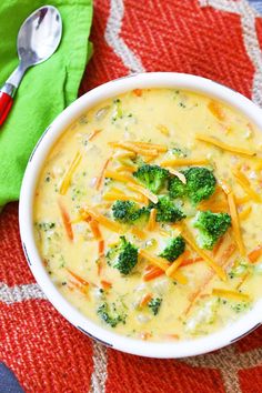 a bowl of broccoli cheese soup on a red and white tablecloth with a spoon