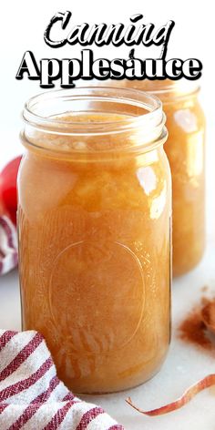 two jars filled with apples sitting on top of a table