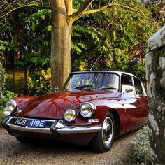 an old red car parked in front of a tree