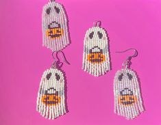 three beaded ghost earrings are shown on a pink background, one is white and the other is orange