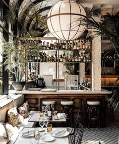 the interior of a restaurant with tables, chairs and potted plants hanging from the ceiling