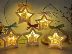 five star shaped lights are sitting on a table next to each other, with bows and ribbons around them