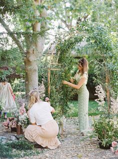 two women are working on an arbor in the middle of a garden with lots of flowers