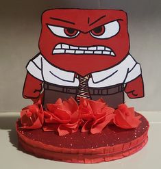 a paper cut out of a cartoon character on top of a red heart shaped cake