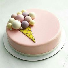 a pink cake topped with an ice cream cone and candy balls on top of it