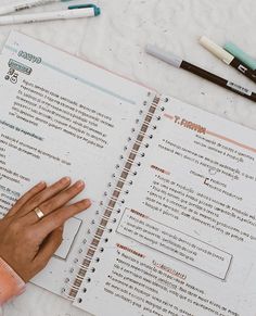 a person's hand is on top of a notebook with writing paper and markers