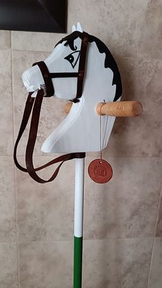 a horse head mounted to the side of a white pole with a brown leather strap