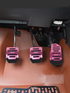 three pink pedals in the center console of a car