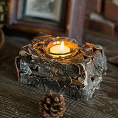 a lit candle sitting on top of a wooden table next to pine cones and other decorations