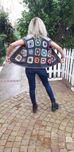 a woman is walking down the street with her back to the camera, wearing a crocheted granny shawl