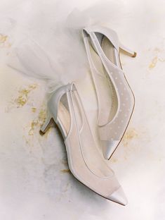 a pair of white high heeled shoes sitting on top of a table next to a tulle