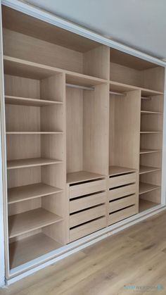 an empty walk in closet with wooden shelves and drawers on the wall next to hardwood flooring