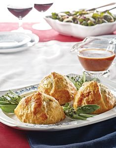 three croissants on a plate with dipping sauce and salad in the background