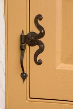 an iron door handle on the side of a yellow door