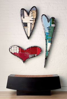 three heart shaped metal pieces on top of a wooden table next to a white brick wall