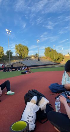 two people sitting on the ground at a baseball field