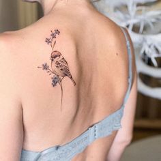 a woman with a bird tattoo on her back shoulder and behind her is a blue dress