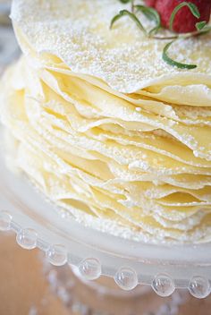 a stack of pancakes covered in powdered sugar and topped with a strawberry on top