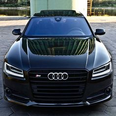 the front end of a black car parked in a parking lot next to a building