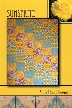 a yellow rose sitting on top of a table next to a quilted wall hanging