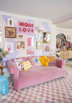 a living room with pink couches and pictures on the wall above them, in front of a checkered rug