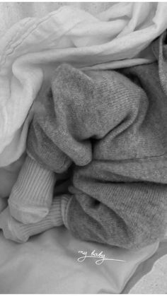 a pile of folded clothes sitting on top of a bed next to a white blanket