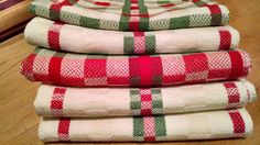 four red and green plaid towels stacked on top of each other in front of a mirror