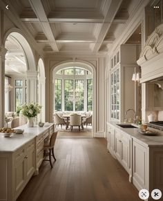 a large kitchen with white cabinets and wooden floors, along with an arched doorway leading to the dining room