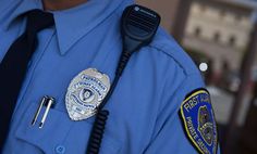 a police officer wearing a blue uniform with a badge on his chest and a microphone attached to his neck