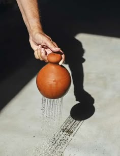 a person is pouring water from a brown jug