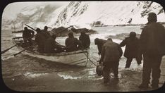 a group of people standing in the water next to a boat