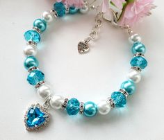 a bracelet with blue and white pearls, heart shaped crystal beads and a silver charm