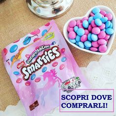 a bag of pink and blue candy next to a heart shaped bowl of small candies