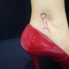 a small tattoo on the ankle of a woman's foot with a red shoe