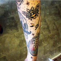 a tattoo on the leg of a person with a bee and other things around it